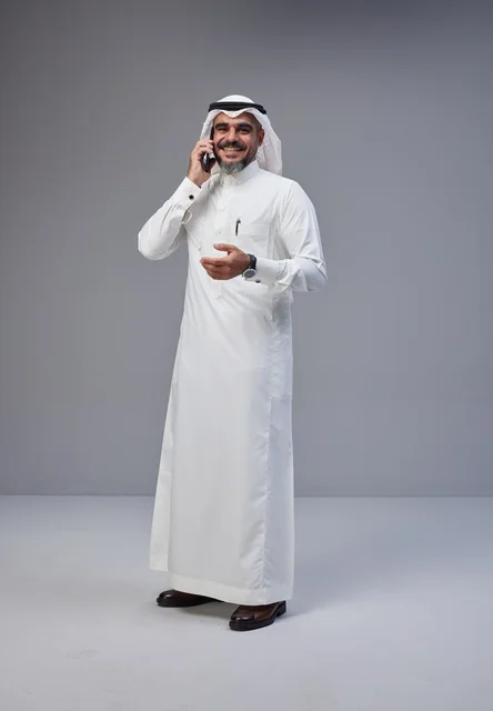 Saudi Man in Traditional Thobe Talking on Smartphone