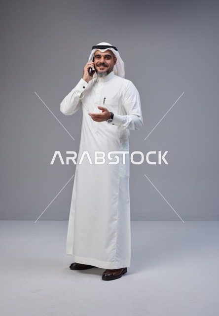 رجل سعودي بالزي التقليدي يتحدث عبر الهاتف المحمول