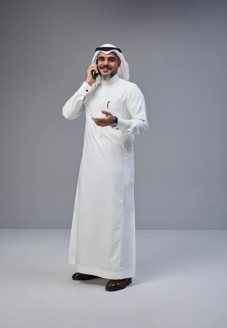 Saudi Man in Traditional Thobe Talking on Smartphone