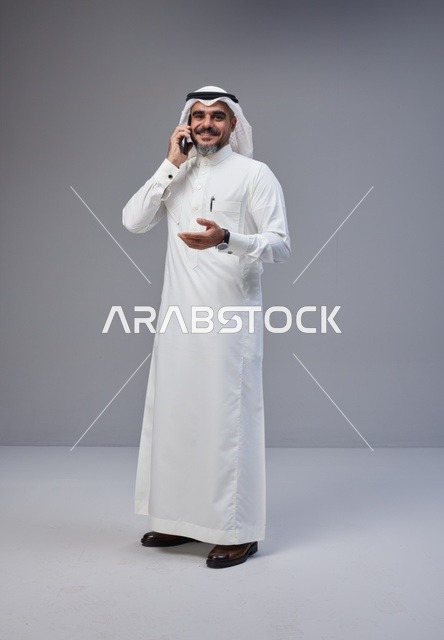 Saudi Man in Traditional Thobe Talking on Smartphone
