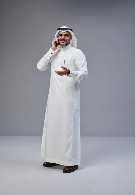 رجل سعودي بالزي التقليدي يتحدث عبر الهاتف الذكي