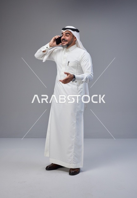 رجل سعودي بالزي التقليدي يتحدث عبر الهاتف الذكي