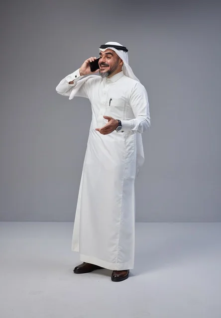 Saudi Man in Traditional Thobe Talking on Smartphone