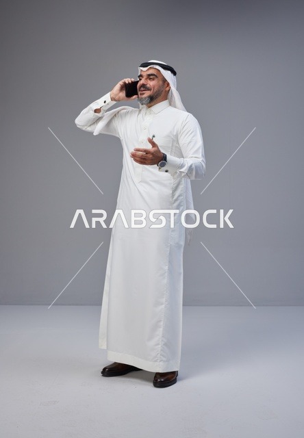 Saudi Man in Traditional Thobe Talking on Smartphone