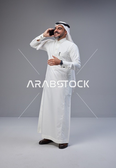 Saudi Man in Traditional Thobe Talking on Smartphone