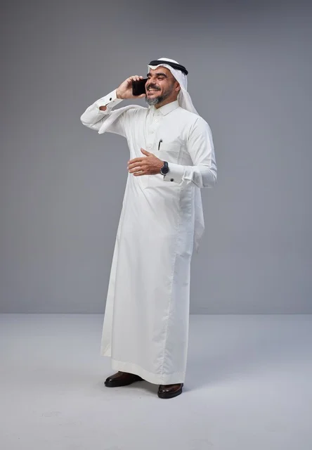 Saudi Man in Traditional Thobe Talking on Smartphone