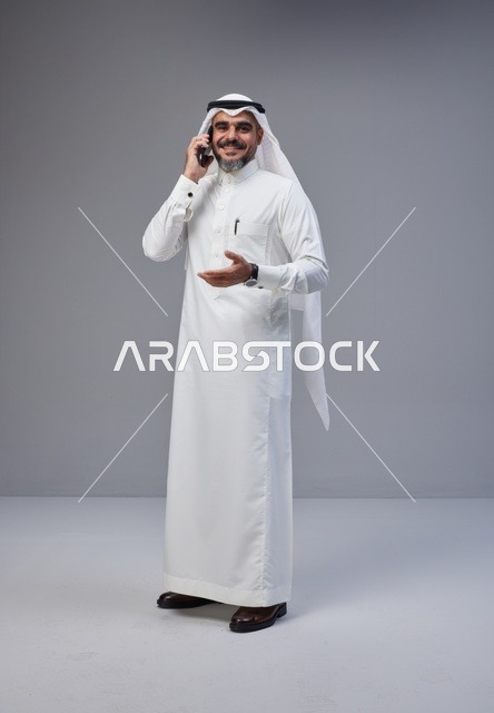 Saudi Man in Traditional Thobe Talking on Smartphone