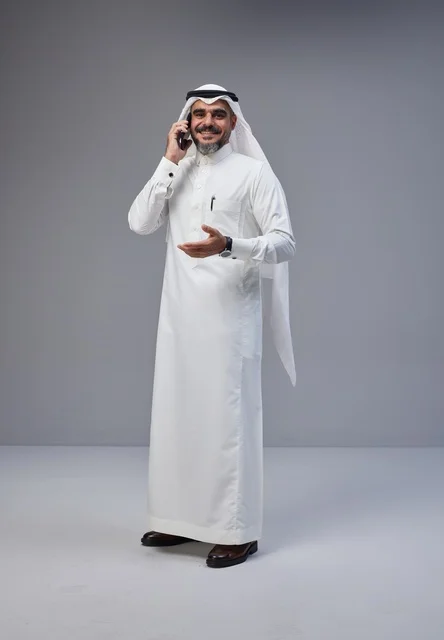 Saudi Man in Traditional Thobe Talking on Smartphone