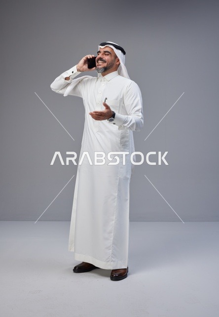 رجل سعودي بالزي التقليدي يتحدث عبر الهاتف المحمول