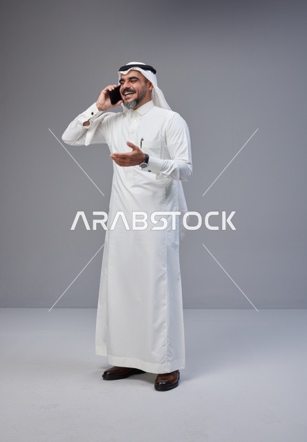 Saudi Man in Traditional Thobe Talking on Smartphone