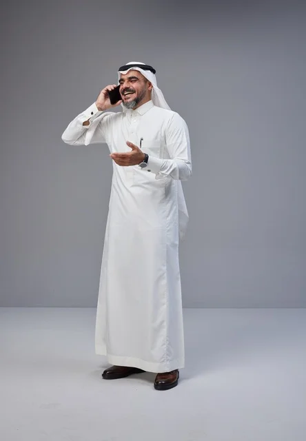 Saudi Man in Traditional Thobe Talking on Smartphone