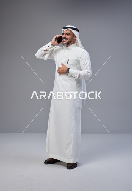 Saudi Man in Traditional Thobe Talking on Smartphone