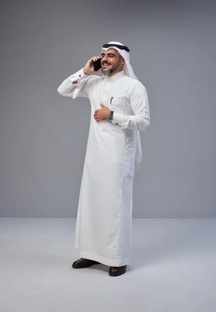 Saudi Man in Traditional Thobe Talking on Smartphone