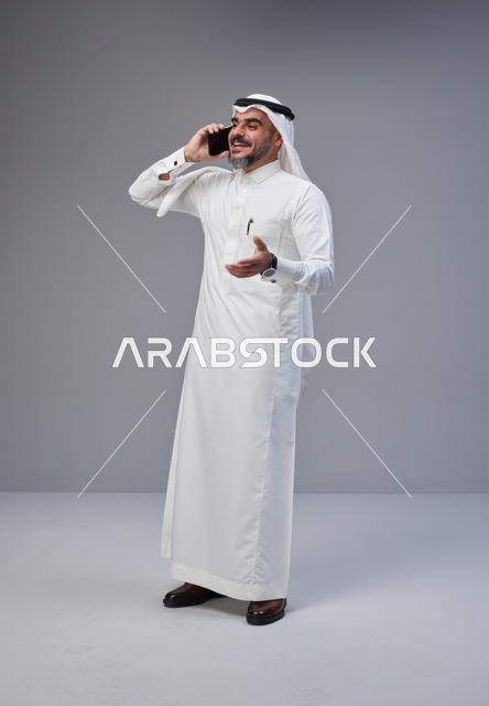 رجل سعودي بالزي التقليدي يتحدث عبر الهاتف الجوال