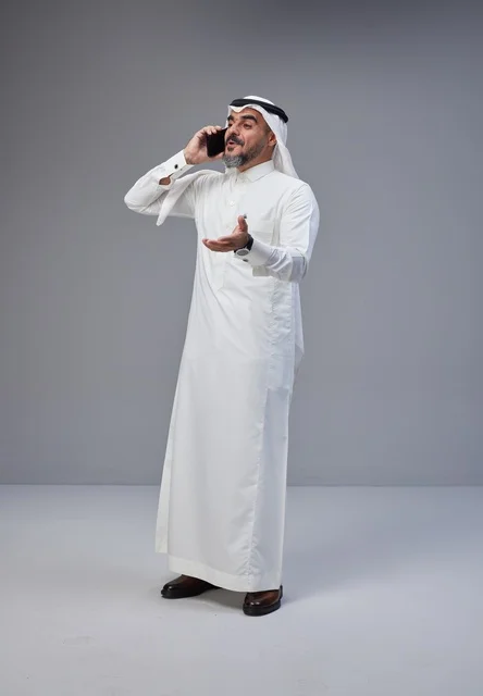 Saudi man in traditional attire talking on phone with expressive gesture