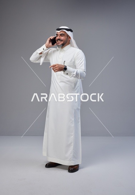 رجل سعودي بالزي التقليدي يتحدث عبر الهاتف الجوال