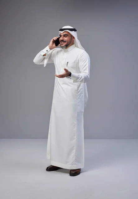 رجل سعودي بالزي التقليدي يتحدث عبر الهاتف الذكي