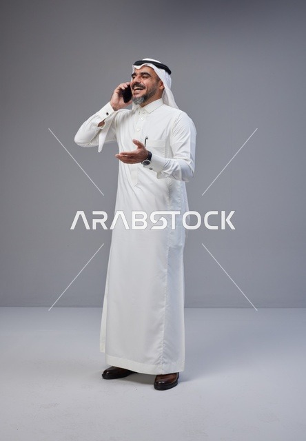 رجل سعودي بالزي التقليدي يتحدث عبر الهاتف الجوال