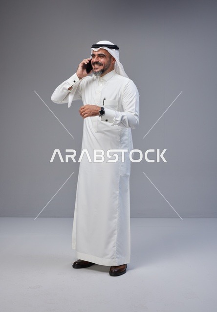 رجل سعودي بالزي التقليدي يتحدث عبر الهاتف الذكي