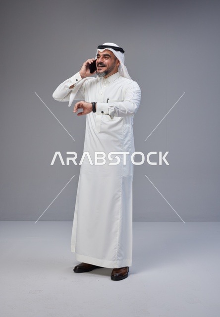 رجل سعودي بالزي التقليدي يتحدث عبر الهاتف الجوال