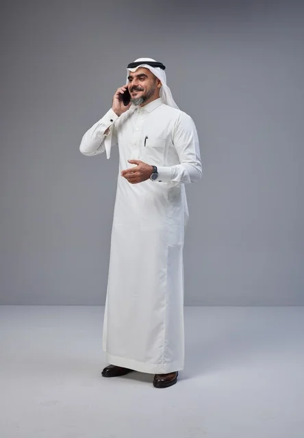 رجل سعودي بالزي التقليدي يتحدث عبر الهاتف الذكي