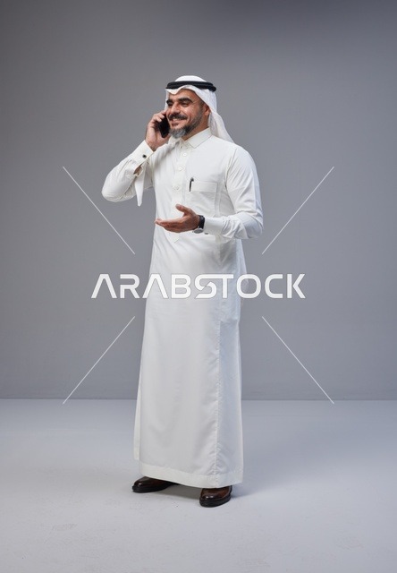 رجل سعودي بالزي التقليدي يتحدث عبر الهاتف المحمول