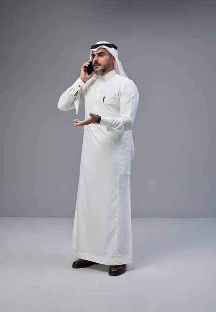 Saudi man in traditional attire talking on phone with expressive gesture