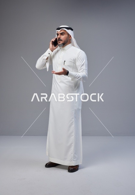 Saudi Man in Traditional Thobe Talking on Smartphone