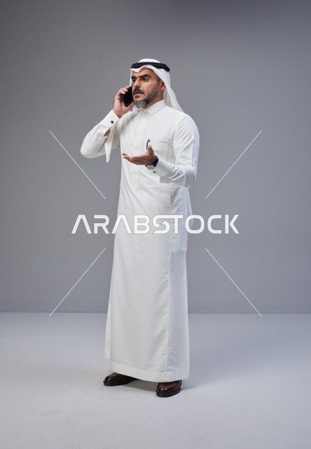 رجل سعودي بالزي التقليدي يتحدث عبر الهاتف المحمول