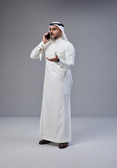 رجل سعودي بالزي التقليدي يتحدث عبر الهاتف المحمول