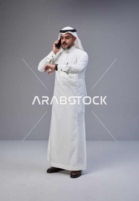 Saudi Man in Traditional Thobe Talking on Smartphone