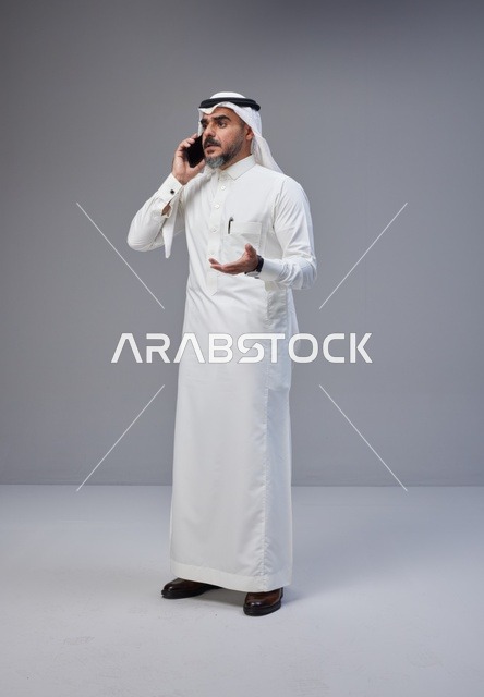 رجل سعودي بالزي التقليدي يتحدث عبر الهاتف الجوال