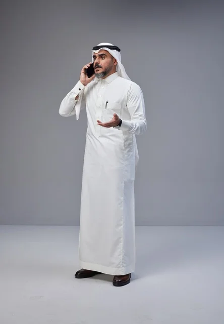 رجل سعودي بالزي التقليدي يتحدث عبر الهاتف الجوال