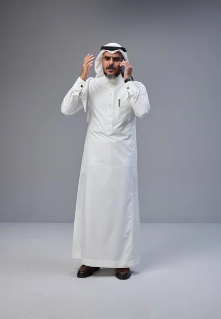 رجل سعودي بالزي التقليدي يتحدث عبر الهاتف بإيماءة