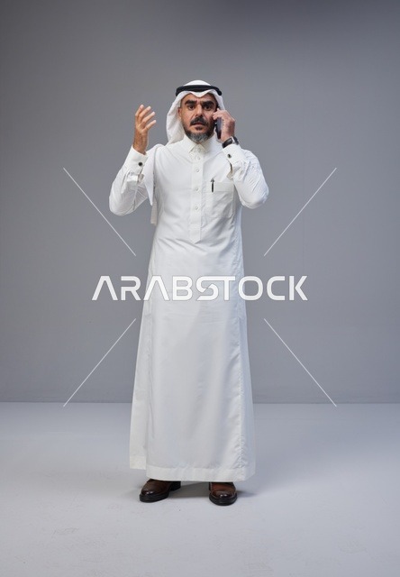 رجل سعودي بالزي التقليدي يتحدث عبر الهاتف المحمول