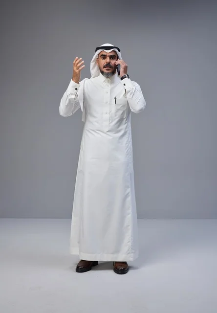 رجل سعودي بالزي التقليدي يتحدث عبر الهاتف المحمول
