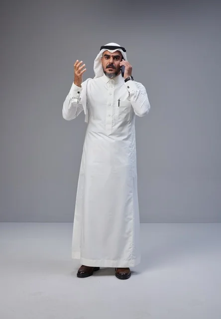 Saudi Man in Traditional Thobe Using Smartphone