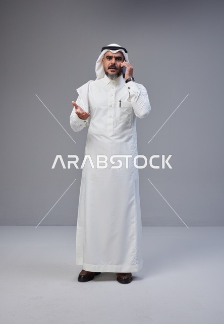 رجل سعودي بالزي التقليدي يتحدث عبر الهاتف الجوال
