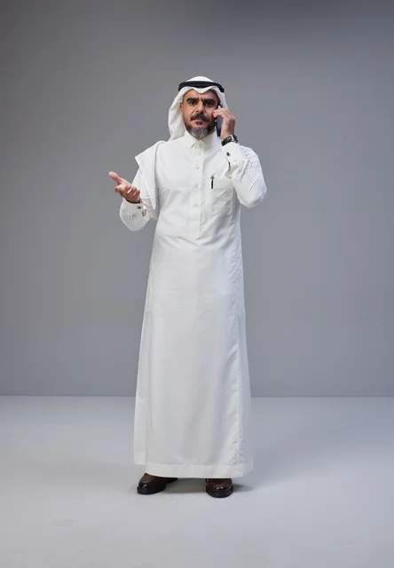 رجل سعودي بالزي التقليدي يتحدث بالهاتف المحمول