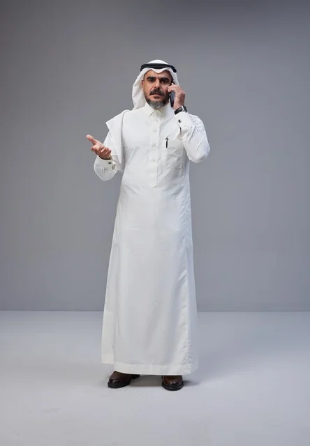 رجل سعودي بالزي التقليدي يتحدث عبر الهاتف المحمول