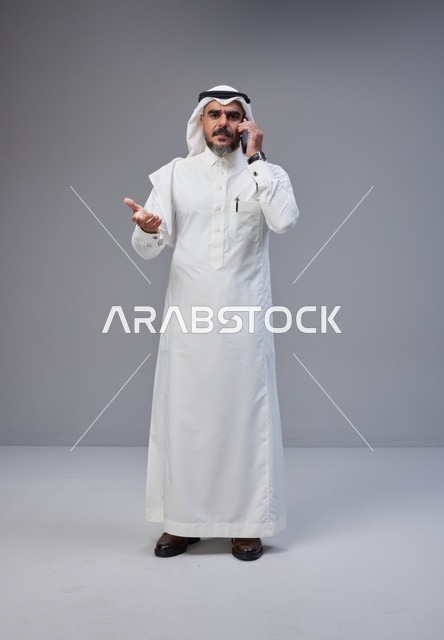 رجل سعودي بالزي التقليدي يتحدث عبر الهاتف الجوال