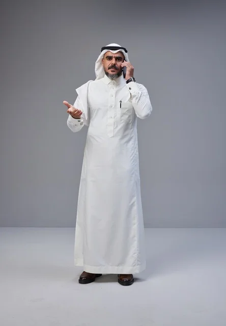 رجل سعودي بالزي التقليدي يتحدث عبر الهاتف الجوال