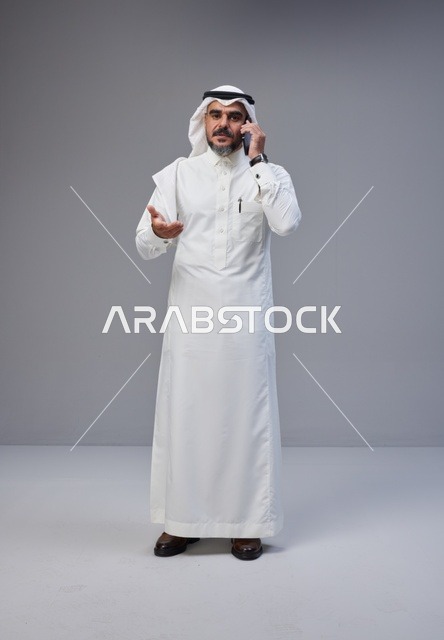Saudi Man in Traditional Thobe Talking on Smartphone