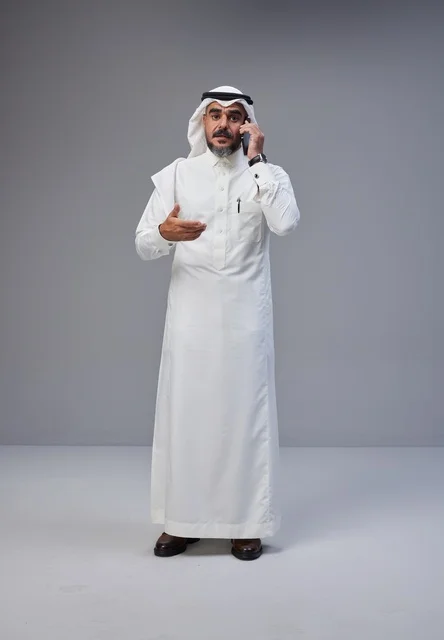 رجل سعودي بالثوب يتحدث بالهاتف مع إيماءة تعبيرية