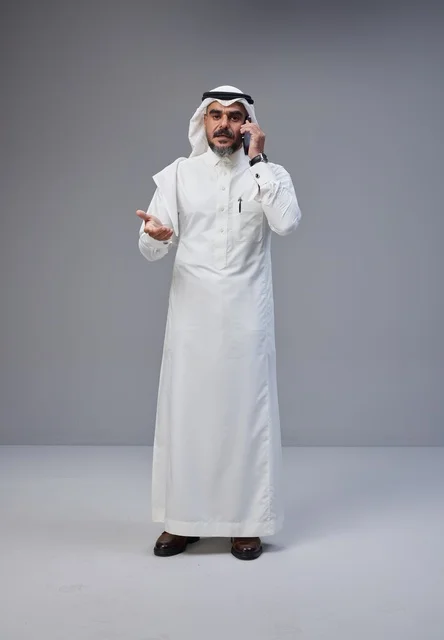 رجل سعودي بالزي التقليدي يتحدث عبر الهاتف الجوال