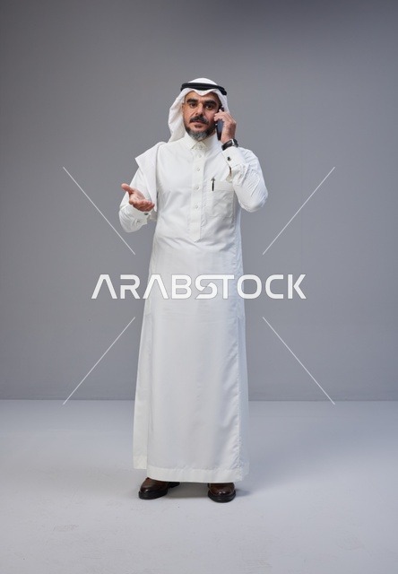 رجل سعودي بالزي التقليدي يتحدث عبر الهاتف الجوال