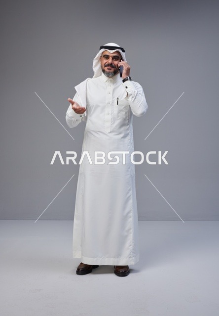 رجل سعودي بالزي التقليدي يتحدث عبر الهاتف المحمول