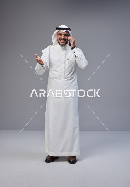 Saudi Man in Traditional Thobe Talking on Smartphone