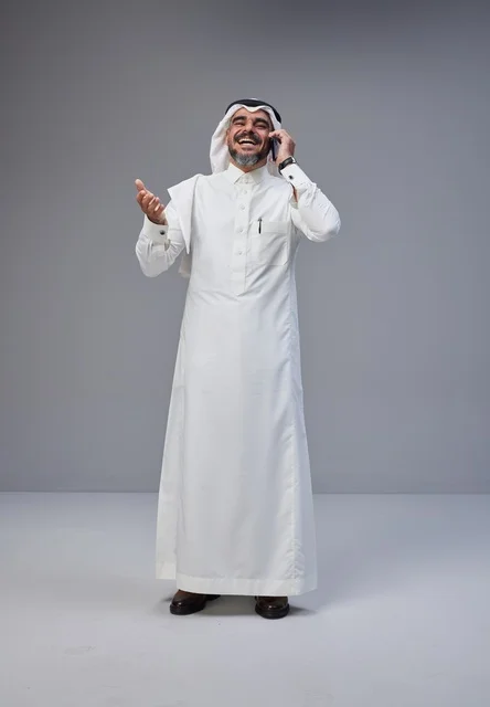 Saudi Man in Traditional Thobe Talking on Smartphone