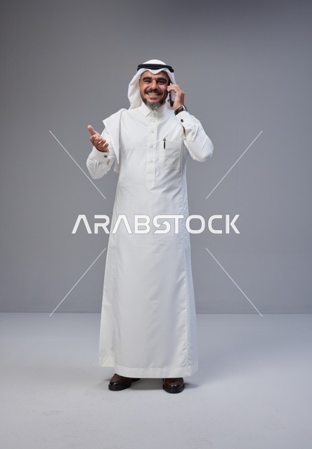 رجل سعودي بالزي التقليدي يتحدث بالهاتف المحمول